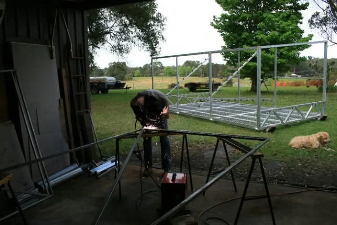 Evan welding a brooder for the 2000 chicks Evan building the first brooder shed at Chicken Caravan