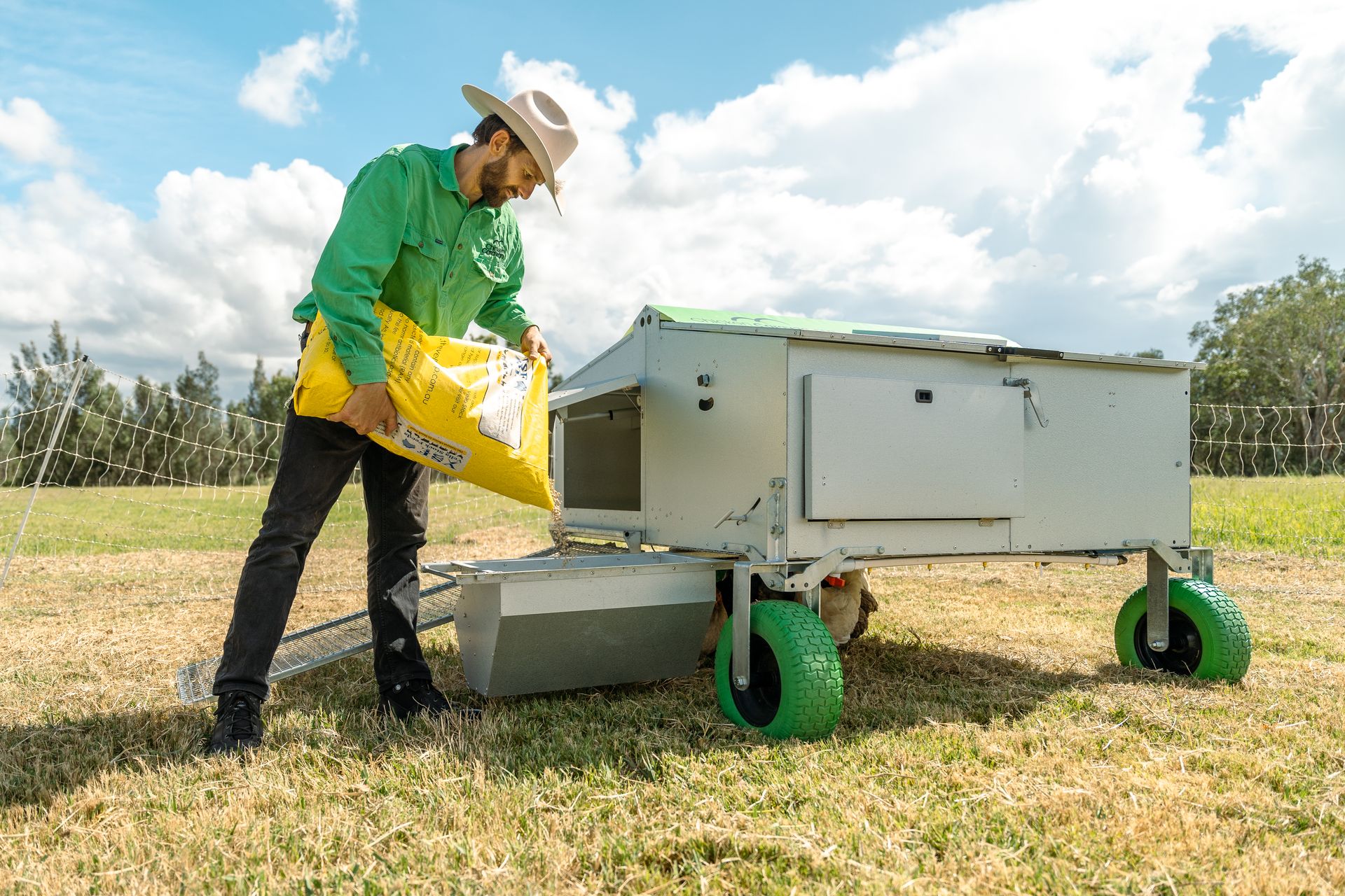 Daniel filling up Chicken Caravan 30 feeder with bag of feed